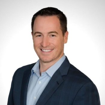 A man wearing a suit and tie smiling for a headshot