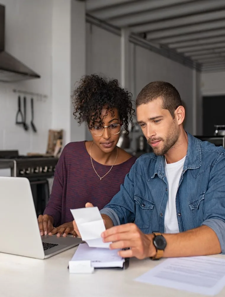 A couple reviewing benefits paperwork together at a laptop