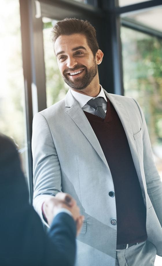 A smiling professional greeting a colleague with a handshake
