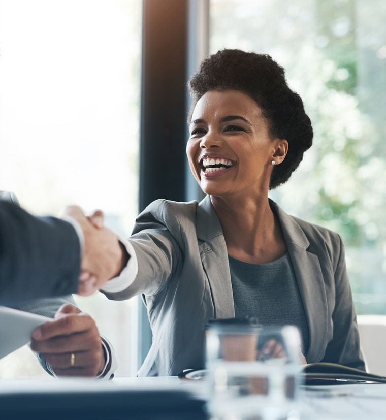 Two business professionals shaking hands across a table